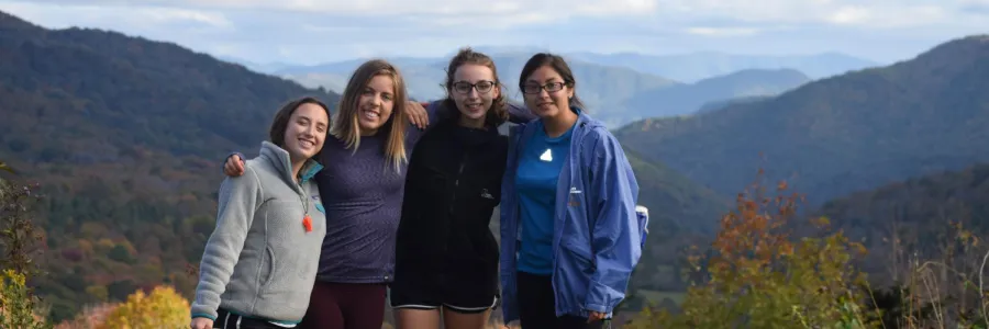 Four students on top of a mountain for a Venture Outdoor Leadership trip