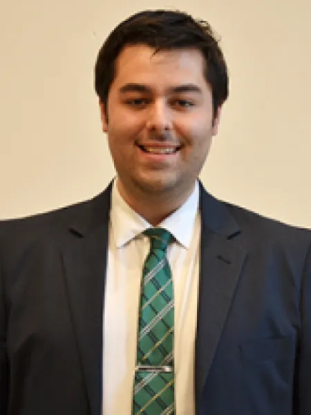 Jeremy Dale smiling in a black suit and green tie